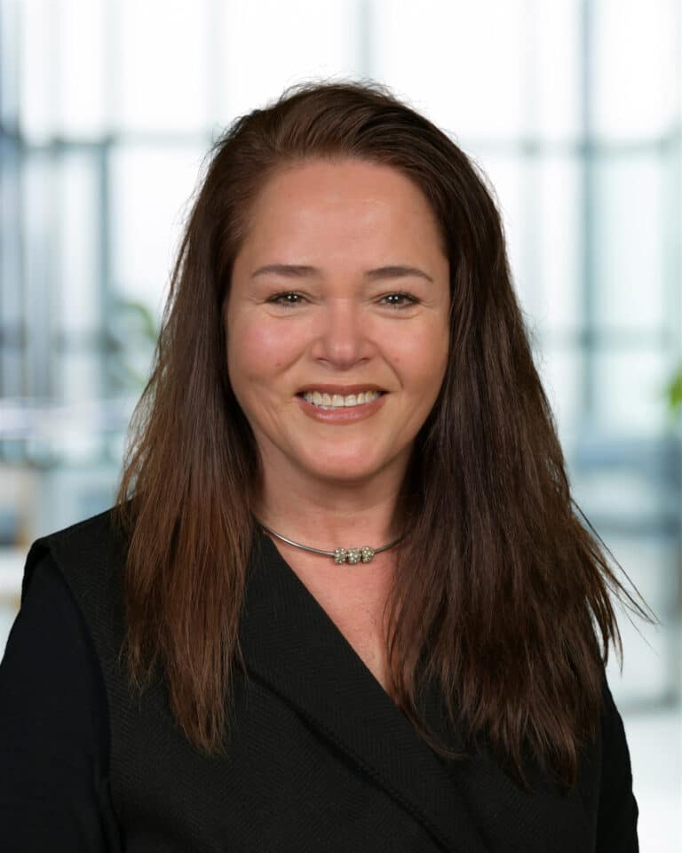 Professional woman smiling in an office setting, exuding confidence and warmth.