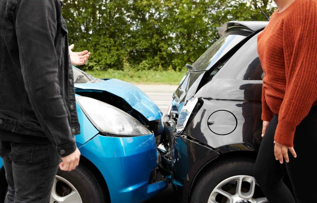 two people standing by cars that have collided