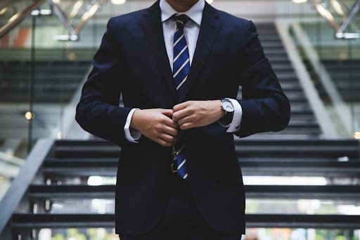 Man in a business suit and tie standing at the bottom of stairs