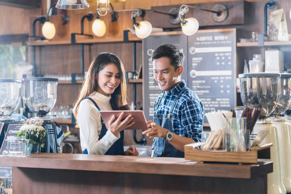 Asian Young Small business owner talking with colleagues and using technology tablet