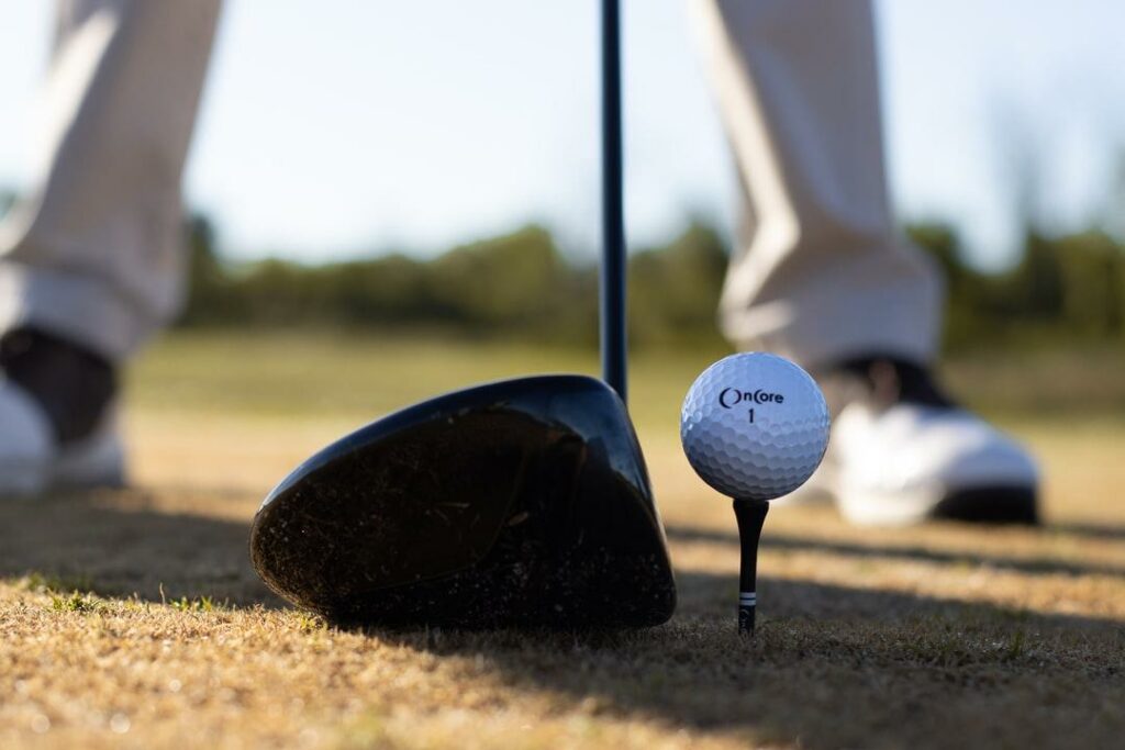 A closeup shot of a golf ball about to be hit with a driver golf club