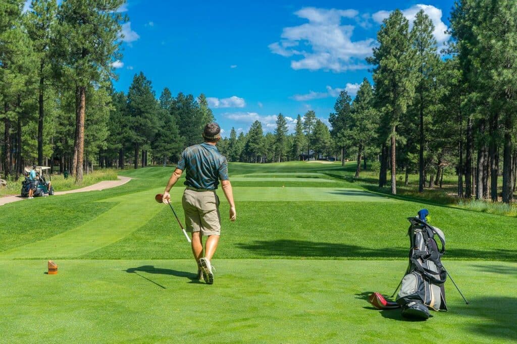 A golfer playing on a golf course on a beautiful sunny day with his golf bag in the foregroound