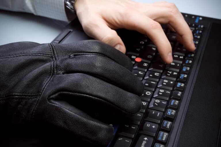 Fake businessman and hacker hands on laptop keyboard