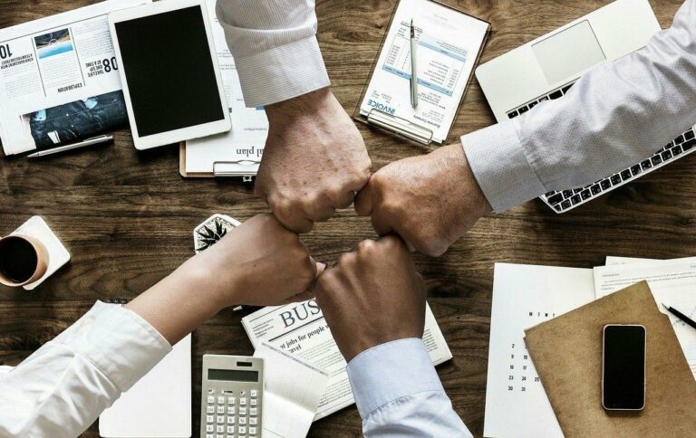 Small business concept 4 fists bumping in the center of a conference table