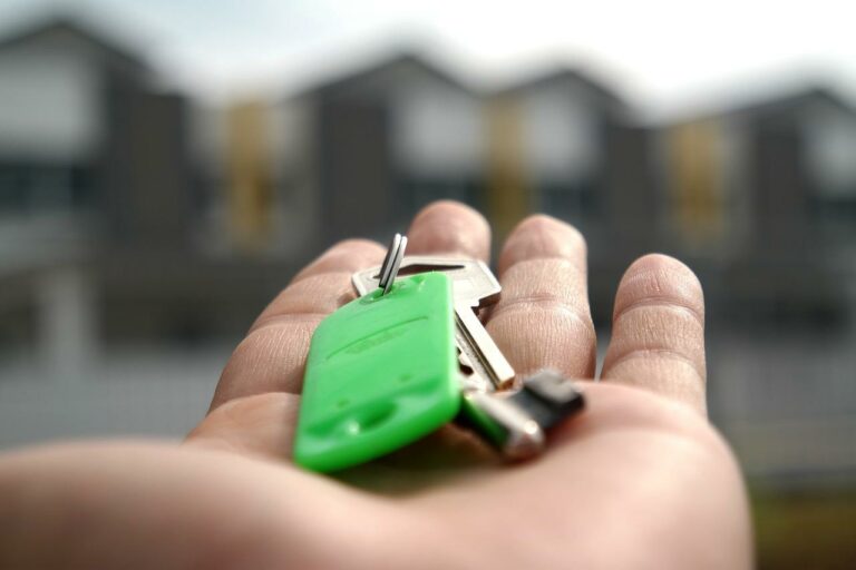 closeup shot of a hand holding a set of keys with an apartment blurred in the background