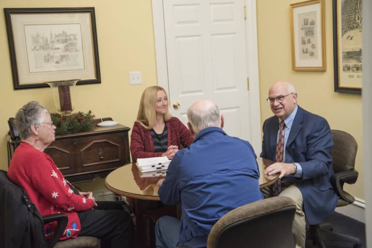 an independent insurance agent and customer service agent having a discussion with an elderly couple