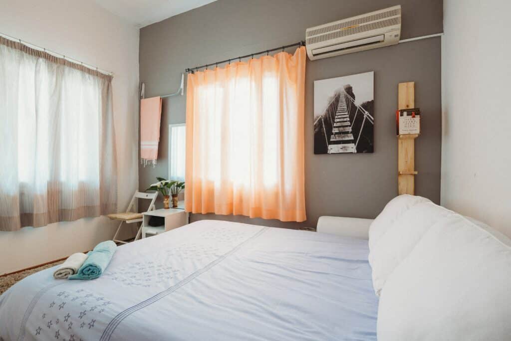 Bedrooom in a short term rental property with the sun shining through an orange curtain.