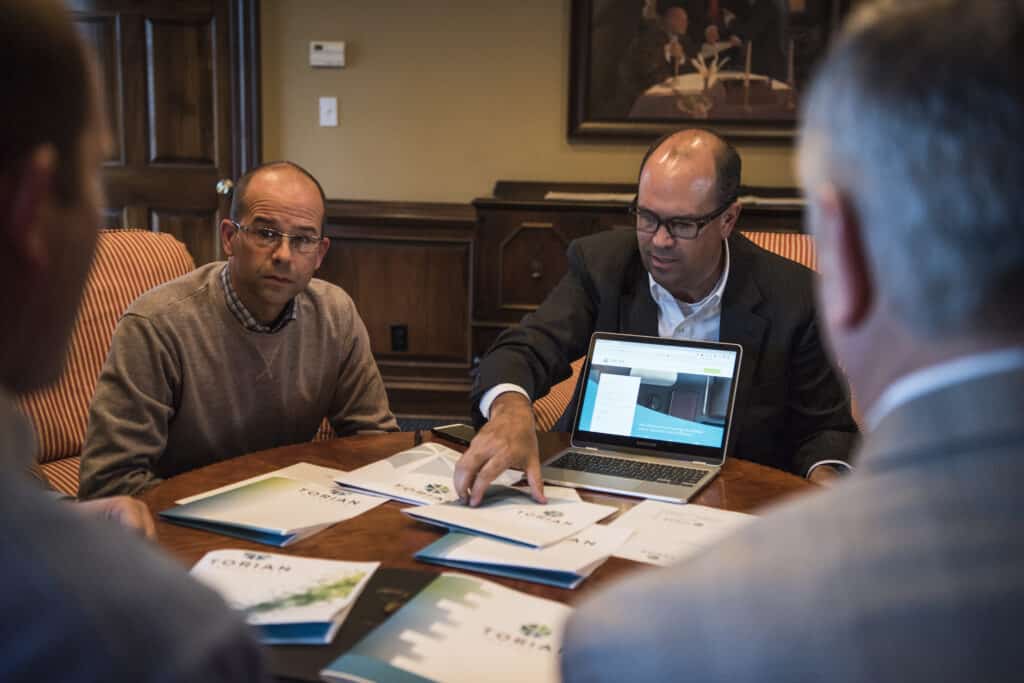 Torian insurance agents sitting around a table at the Torian office with documents and a laptop