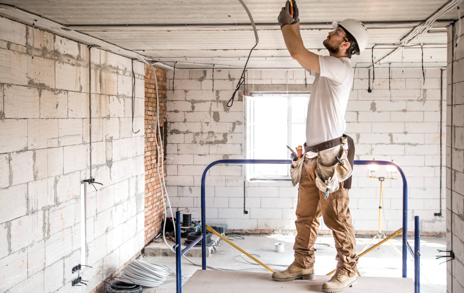 Electrician installer working with cable on the construction site.