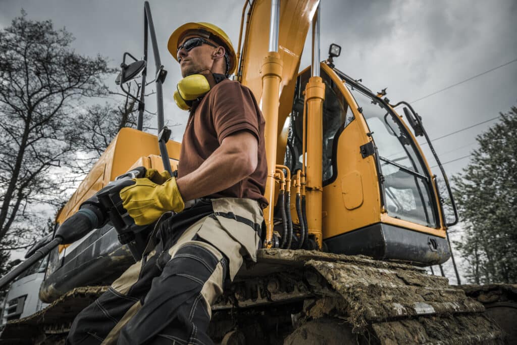 Inland marine contractors insurance concept with man in front of excavator Heavy Duty Machinery Theme.