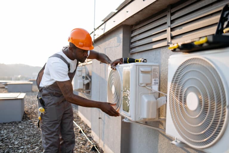 HVAC business concept African american worker installing HVAC outdoors.