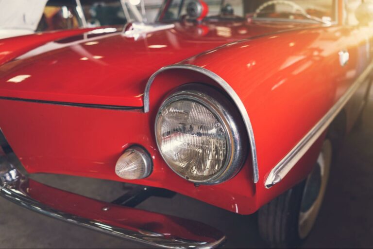 Close-up of a classic red car showcasing its vintage style and charming details.