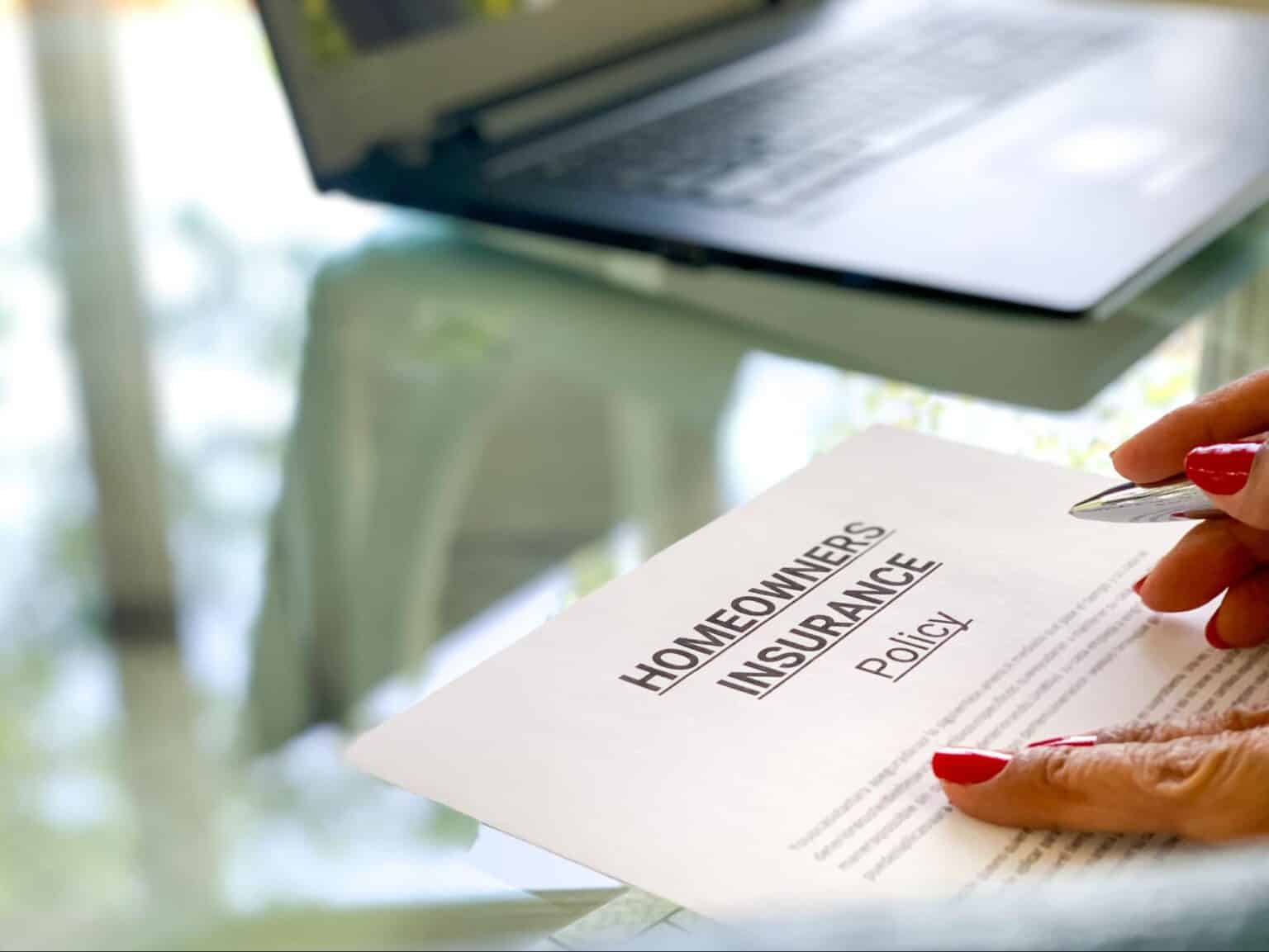Homeowners insurance document with a laptop and a person reviewing details.