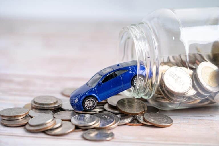 Blue toy car spilling coins from a savings jar for fun money saving.