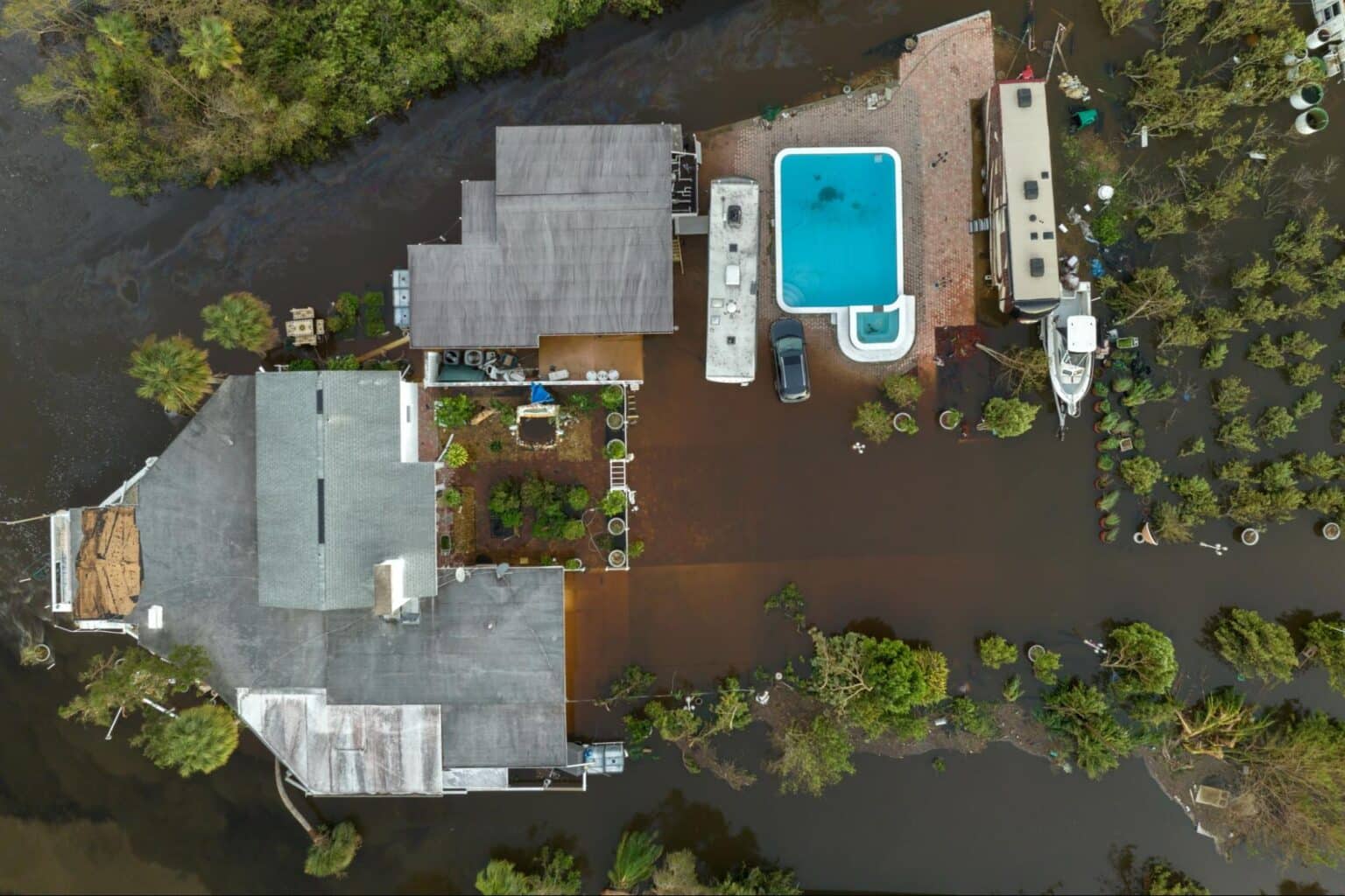 Aerial view of flooded homes with submerged properties and a swimming pool.