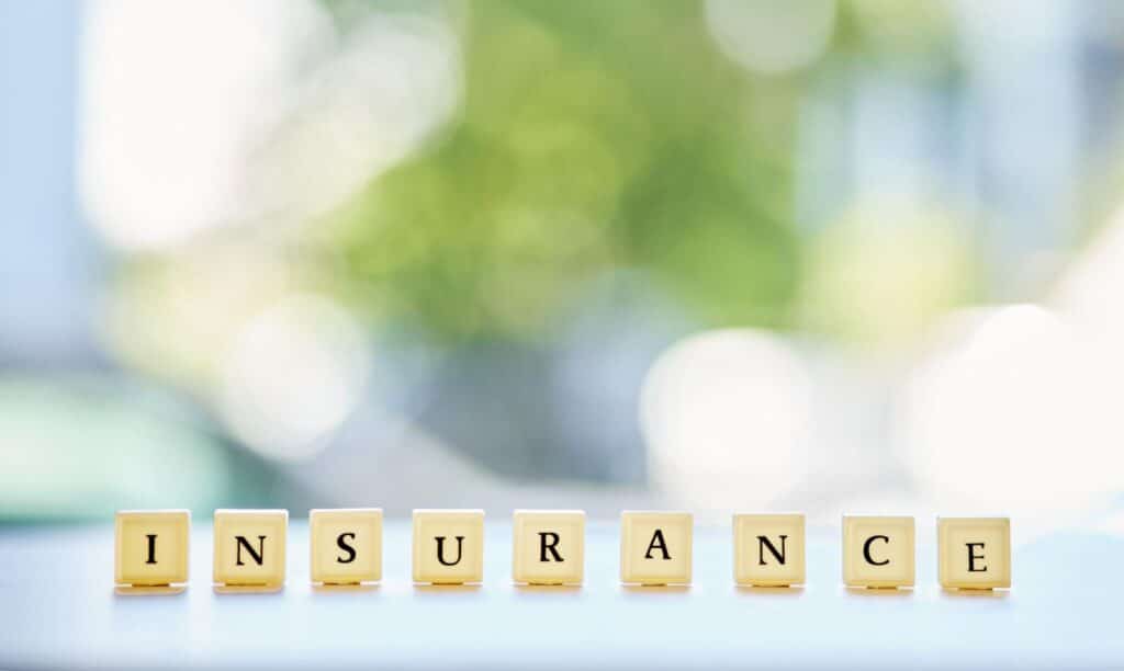 Insurance spelled out in decorative letter tiles against a blurred background.