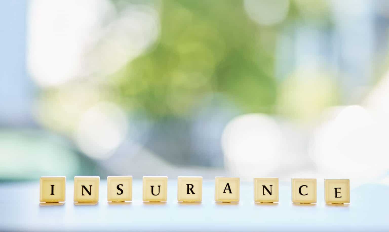 Insurance spelled out in decorative letter tiles against a blurred background.