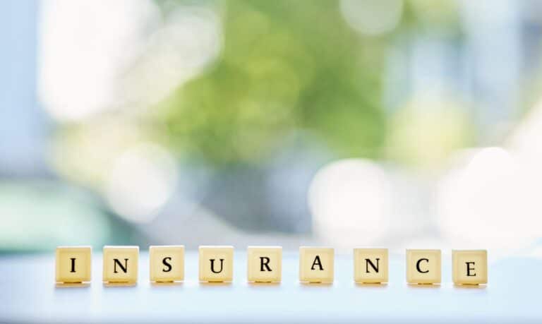 Insurance spelled out in decorative letter tiles against a blurred background.