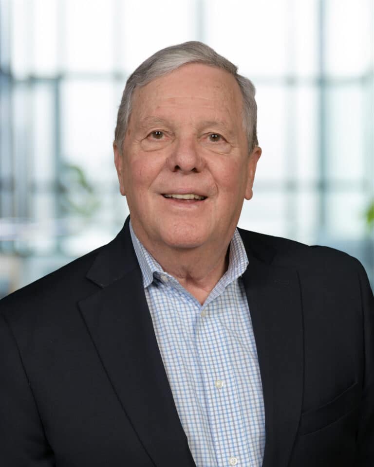 Professional businessman portrait with a warm smile in a modern office setting.