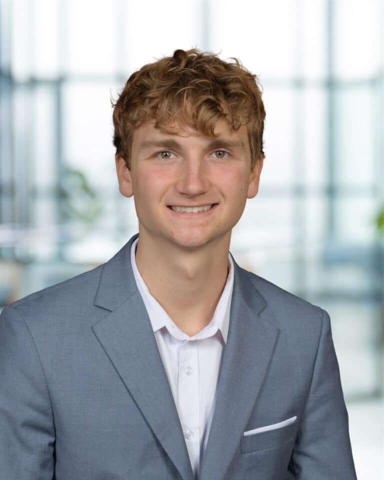 Professional young man in a suit, smiling for a corporate portrait.