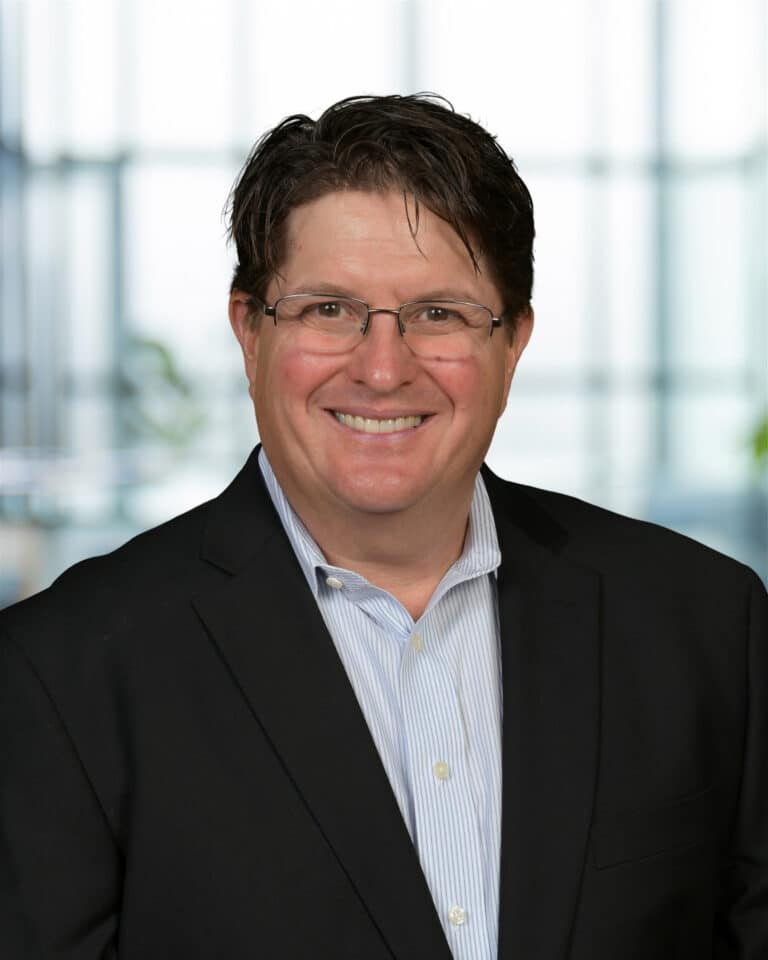 Smiling man in professional attire, showcasing confidence and positivity in a modern office setting.