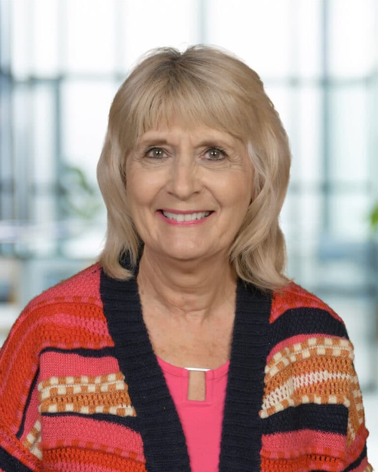 Smiling woman in colorful cardigan, showcasing friendly personality and warm demeanor.