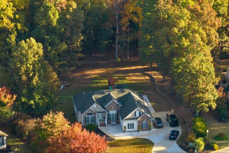 Aerial view of a charming home amid vibrant autumn foliage.