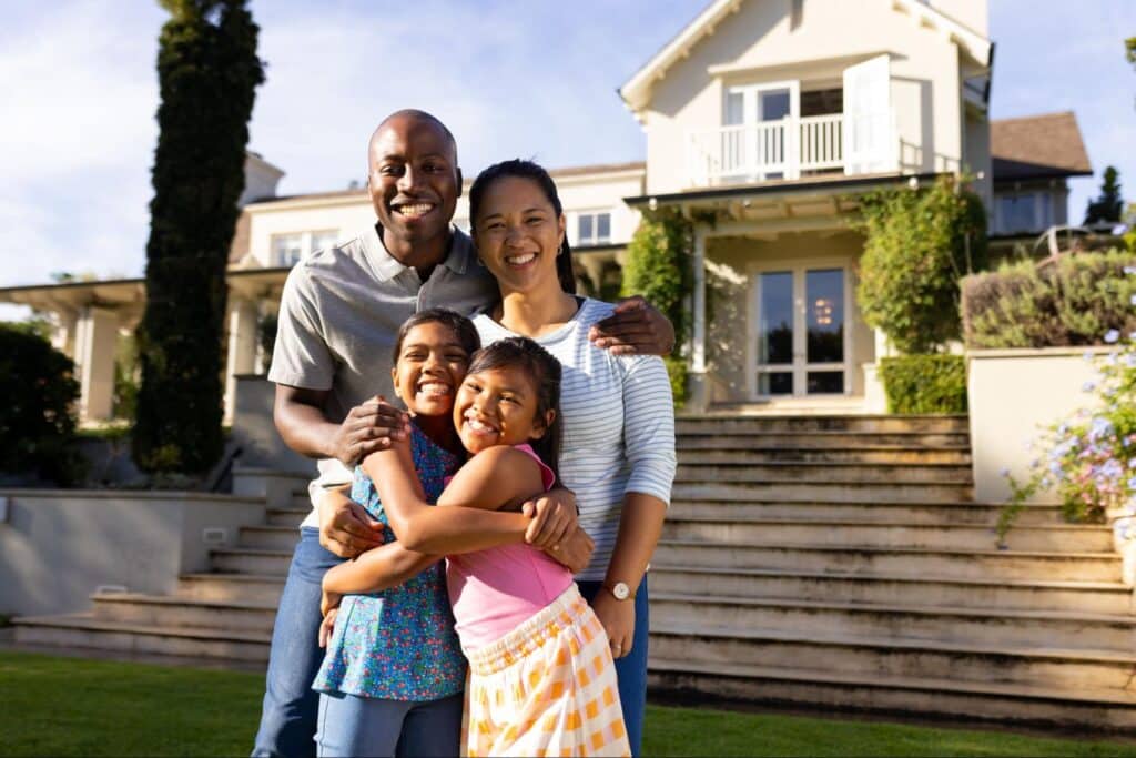 Happy family of four enjoying quality time in front of their beautiful home.