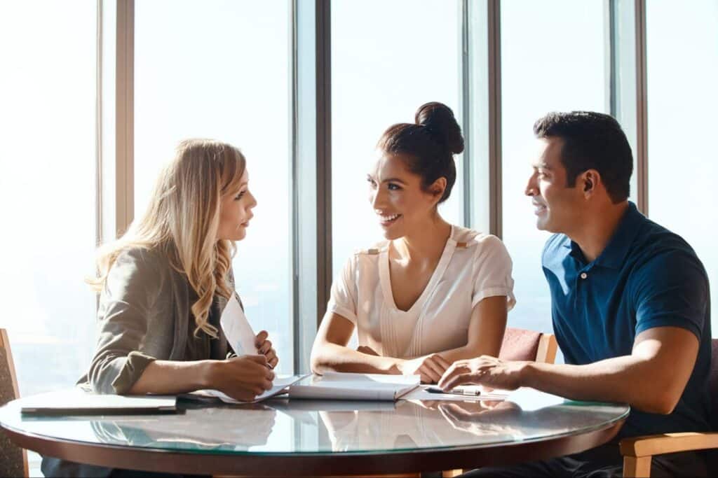 Three colleagues engaged in a productive meeting around a table with a city view.