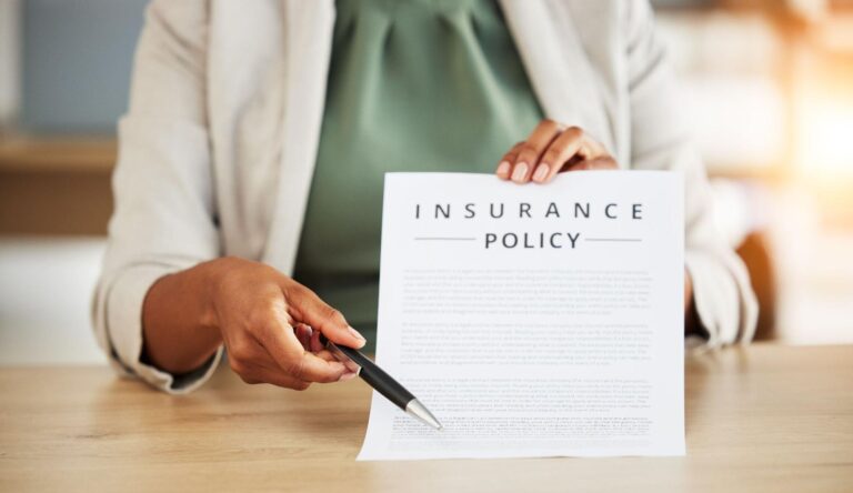 Person reviewing an insurance policy document with a pen.