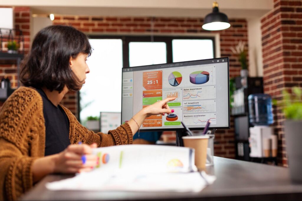 Young woman analyzing data on computer screen in modern office setting.