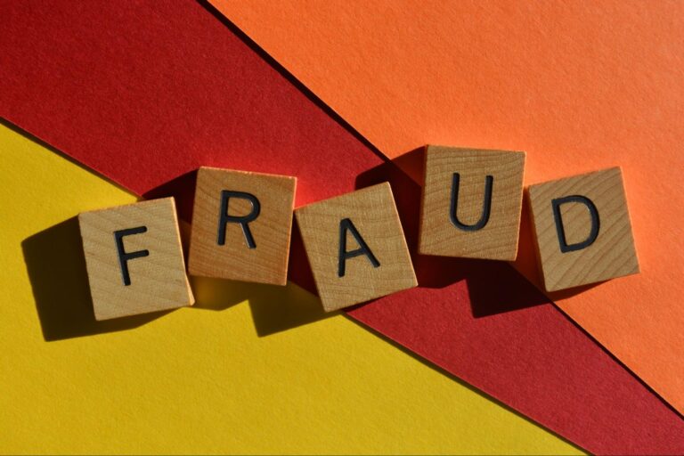 Wooden blocks spelling fraud on vibrant colored background.