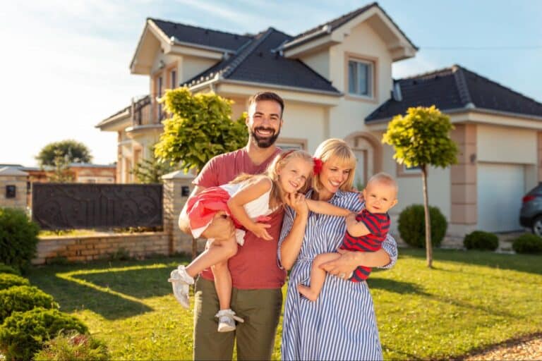 Happy family posing outside their beautiful home in the sunshine.