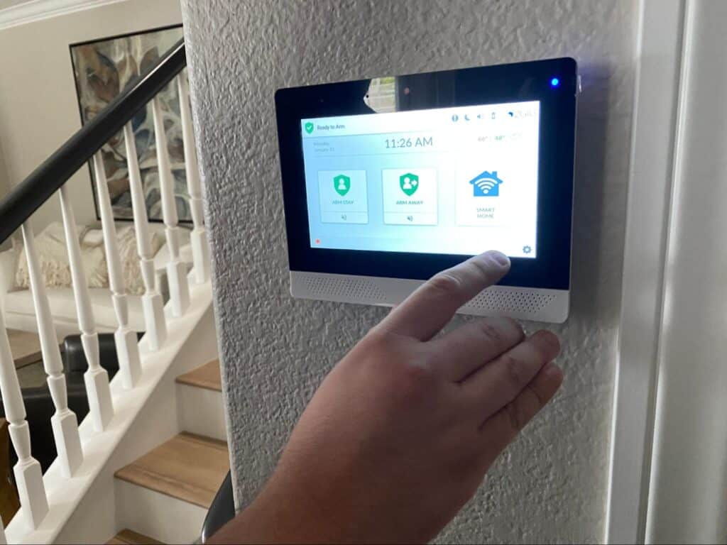Smart home security panel in use, displaying status and controls for safety features.