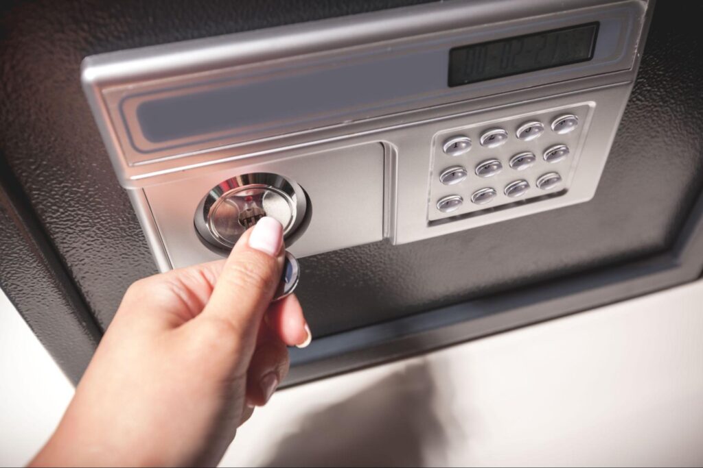 Person using key to unlock digital safe for secure storage.