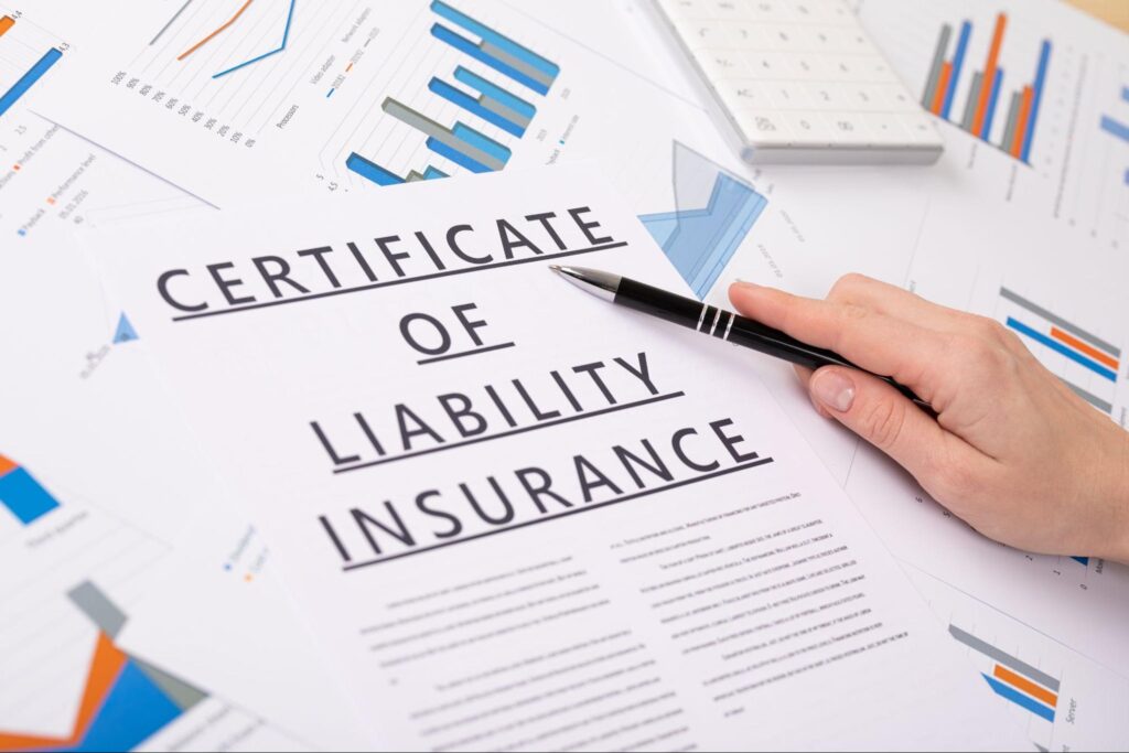 Certificate of liability insurance with graphs and documents on a desk.
