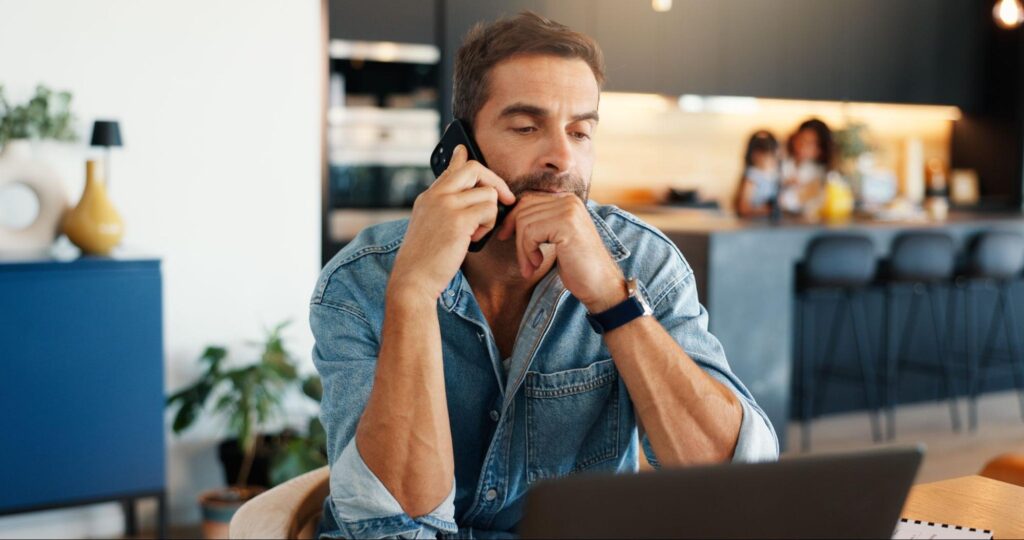 Professional working on a laptop while on the phone in a stylish home office.