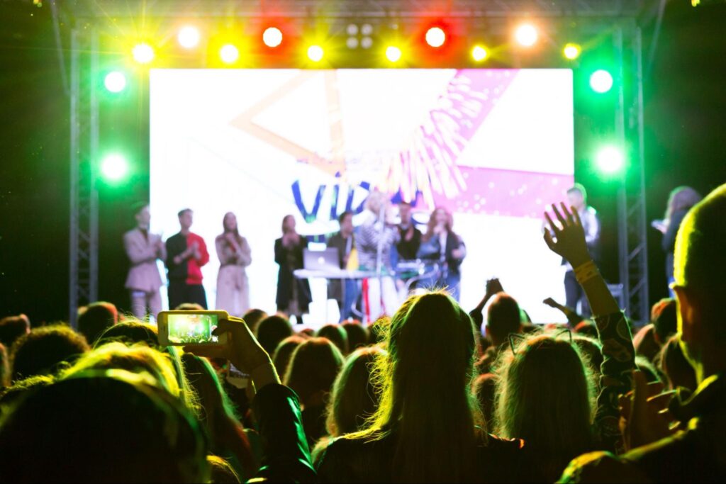 Vibrant fundraiser event with lively audience enjoying colorful performances under dynamic lights.