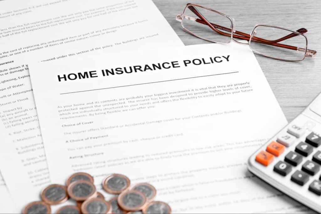 Home insurance policy documents on a desk with glasses and a calculator.