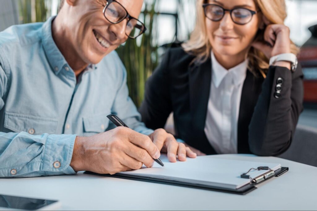 Client confidently signing auto insurance documents with agents guidance.