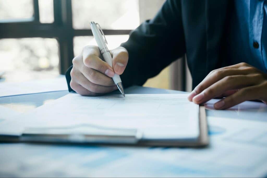 Person signing important documents at a desk during a professional session.